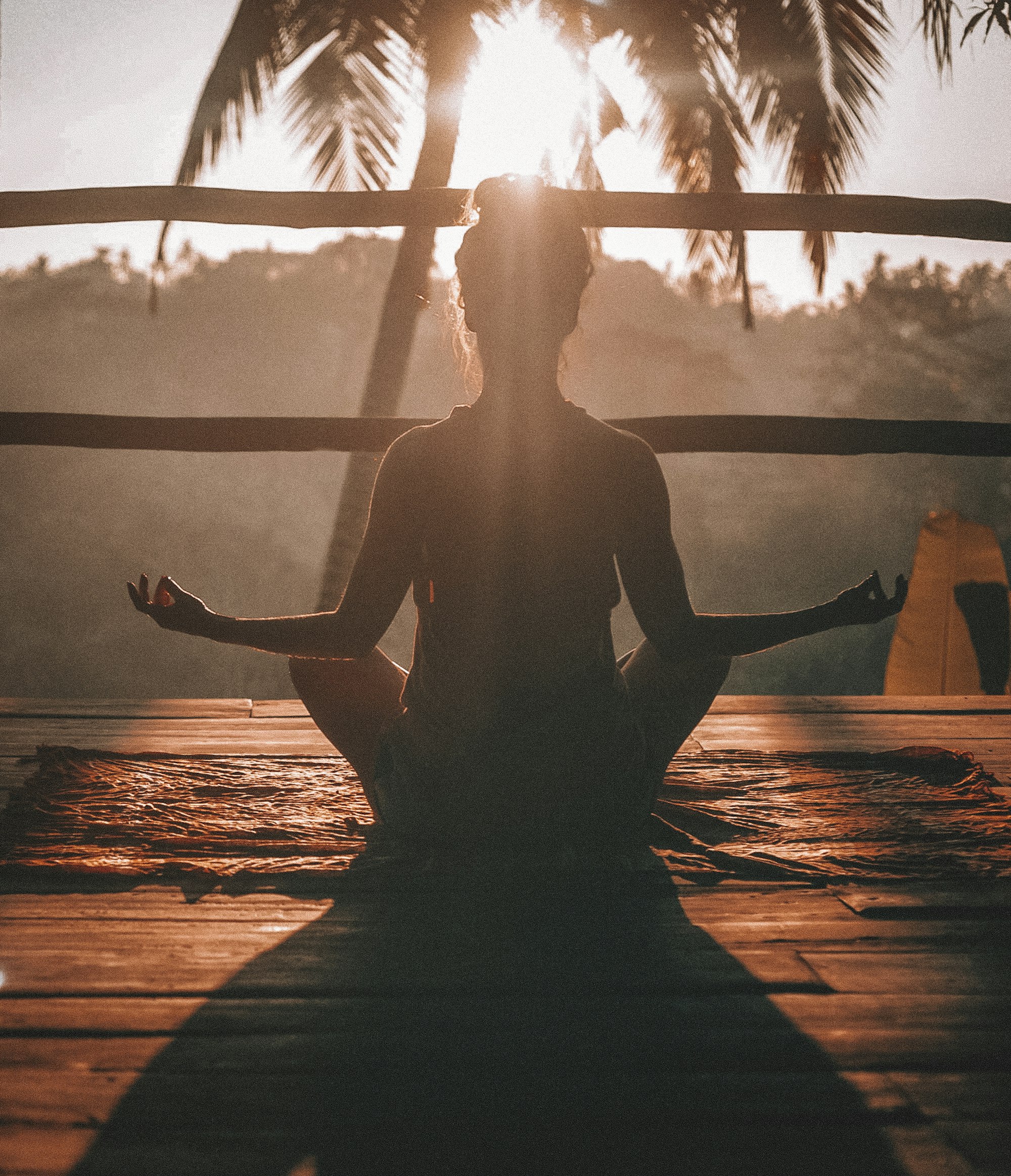 A person sitting cross-legged on a wooden floor in soft morning light