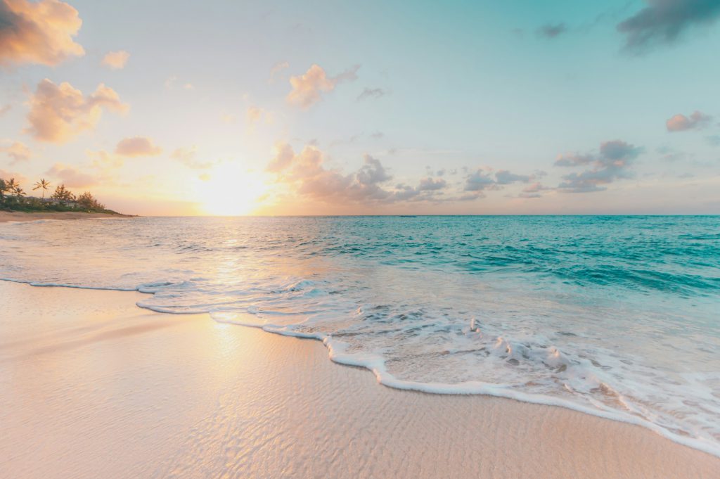 A calm sea meeting a pale sandy beach