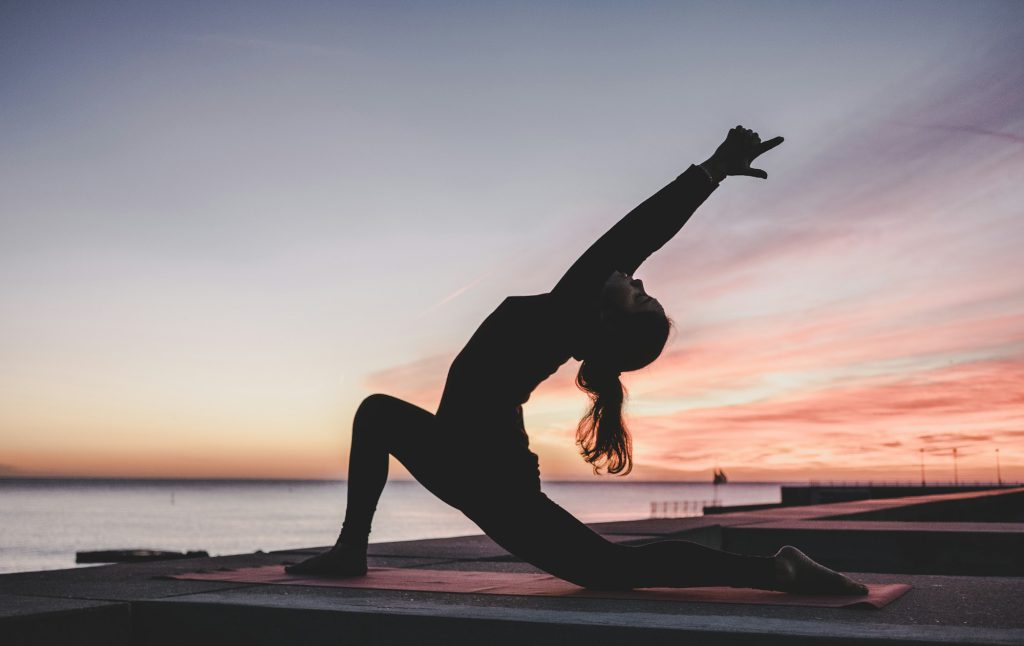 A person stretching slowly on a mat indoors